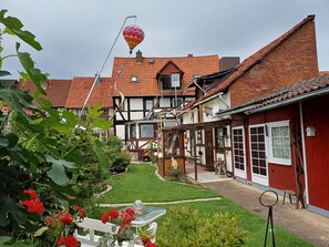 Une cour intérieure européenne traditionnelle, avec un bâtiment à toit rouge, un banc blanc et une montgolfière en arrière-plan.