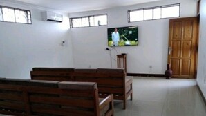 A spacious room with wooden benches, a television mounted on the wall, and a large wooden door.