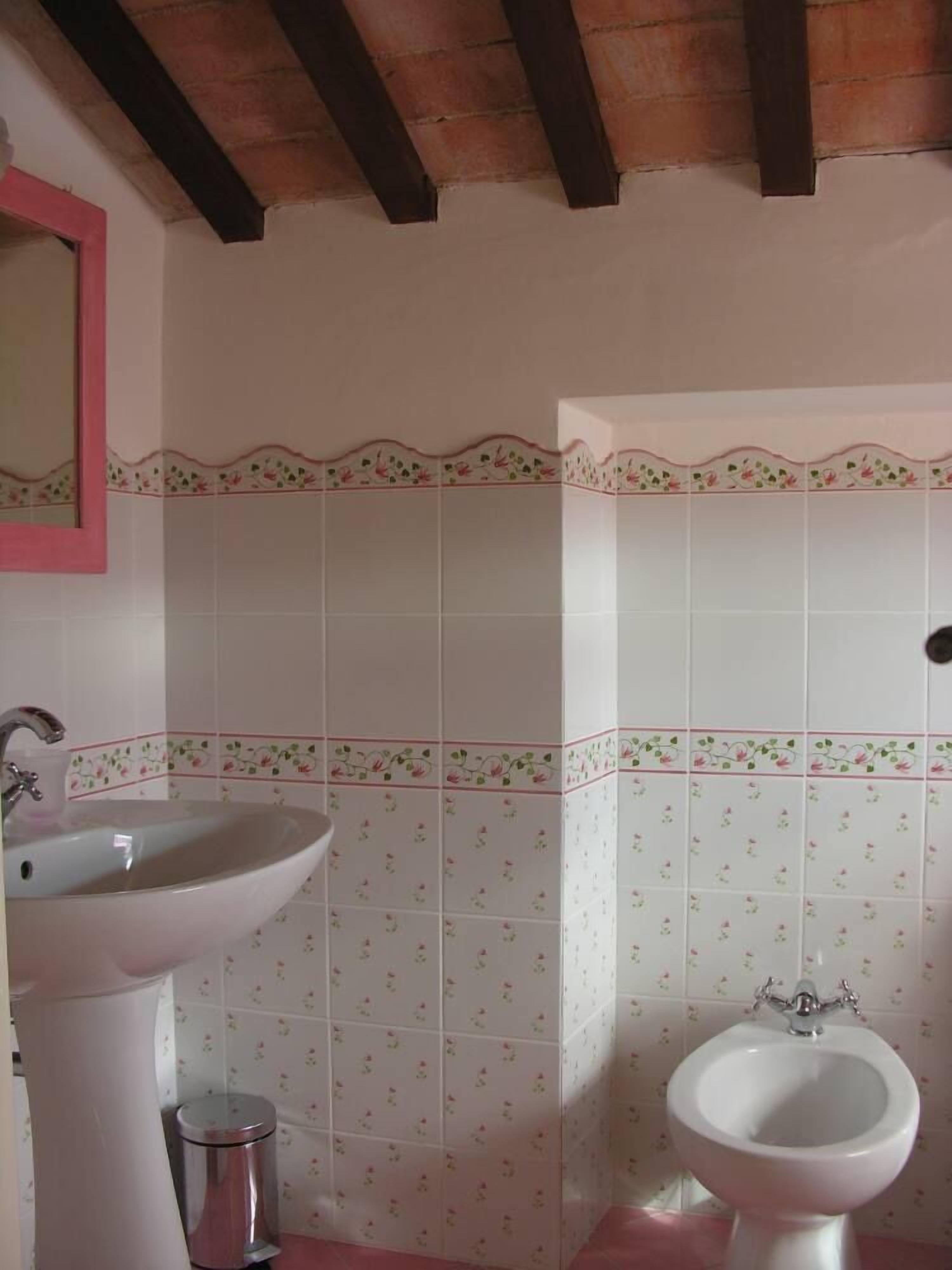 Een badkamer met een wastafel, bidet en prullenbak.