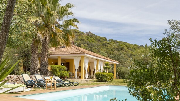 Un espace aménagé au bord de la piscine, avec des chaises longues et un patio couvert.