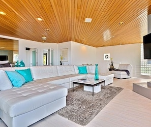 A modern living room with a wooden ceiling, white sofas, and a coffee table.