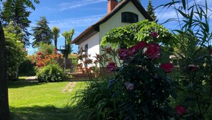 A house with a thatched roof, surrounded by a well-maintained garden with various plants and flowers. - Ferienhaus Wolff, Deutschland (Barth)
