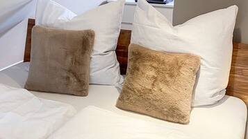 A bed with white bedding and two beige pillows.