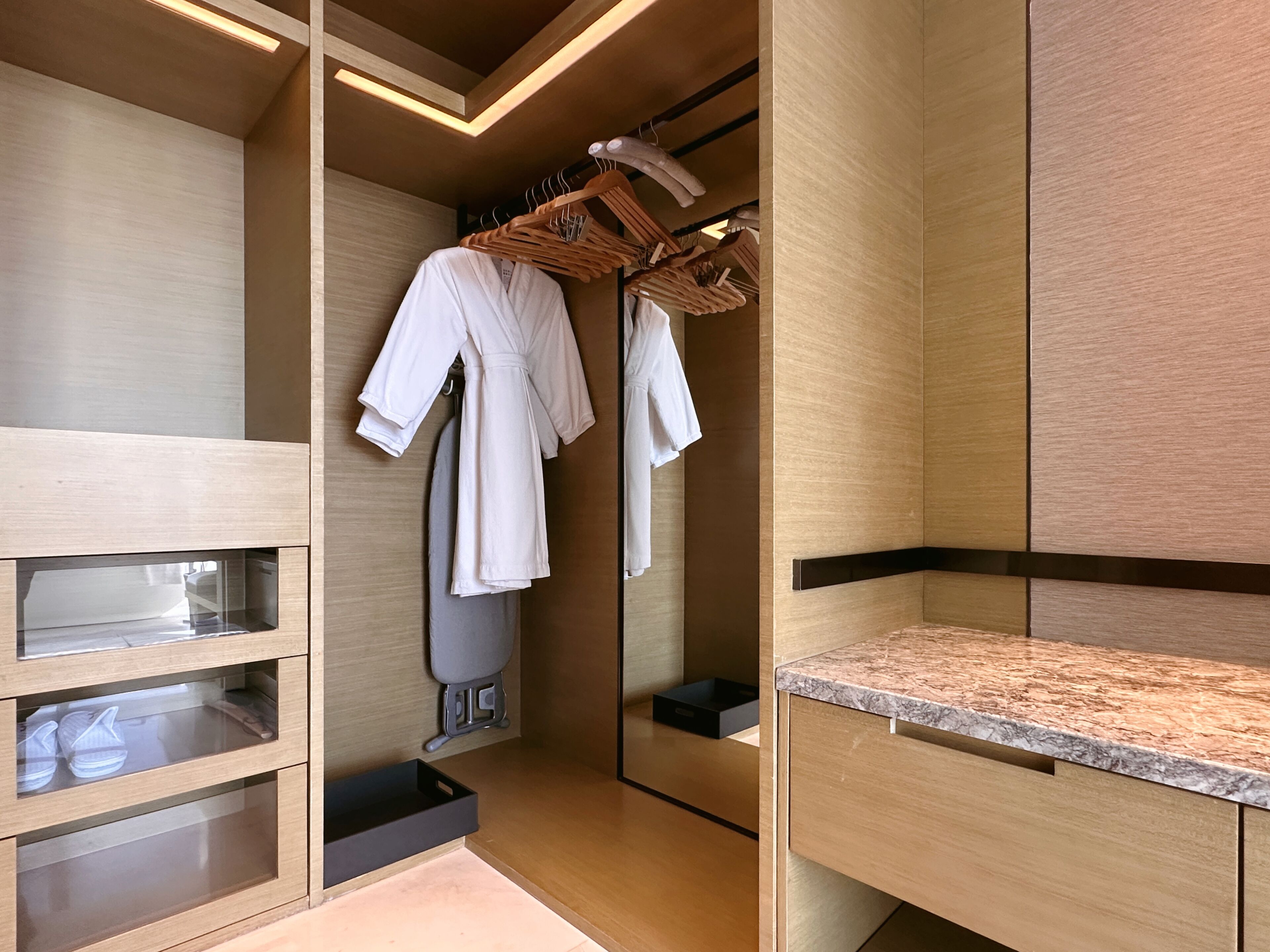 Un baño moderno con muebles de madera, un espejo, un perchero para toallas y una encimera.