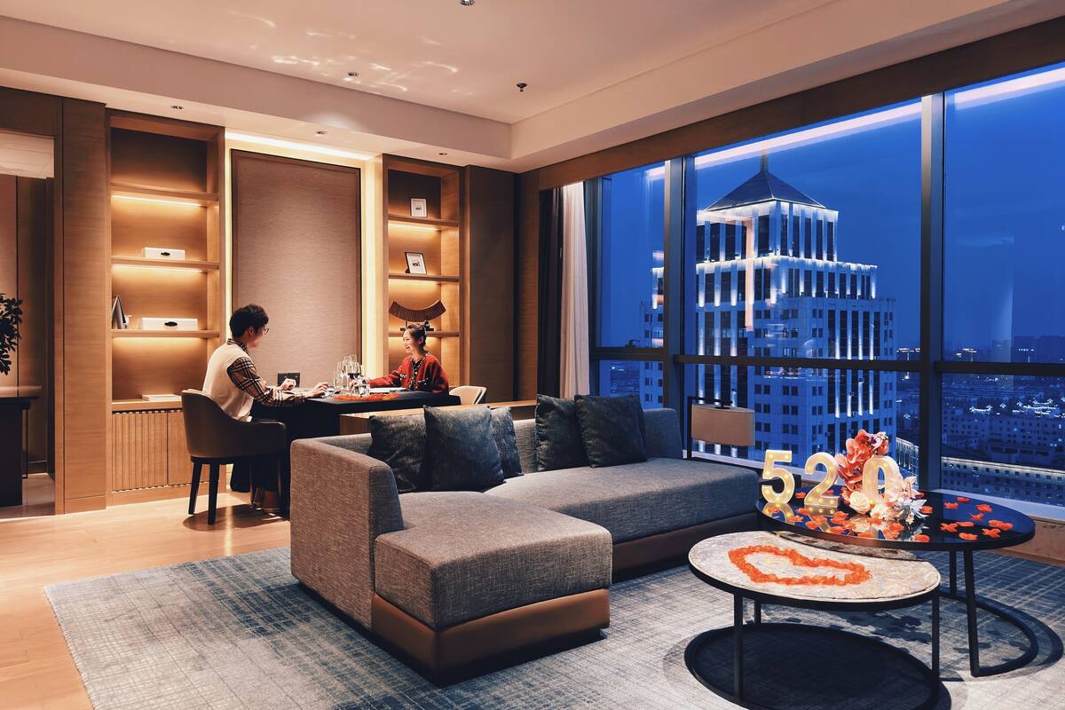 Una sala moderna con un sofá, un comedor y un ventanal con vistas a la ciudad.