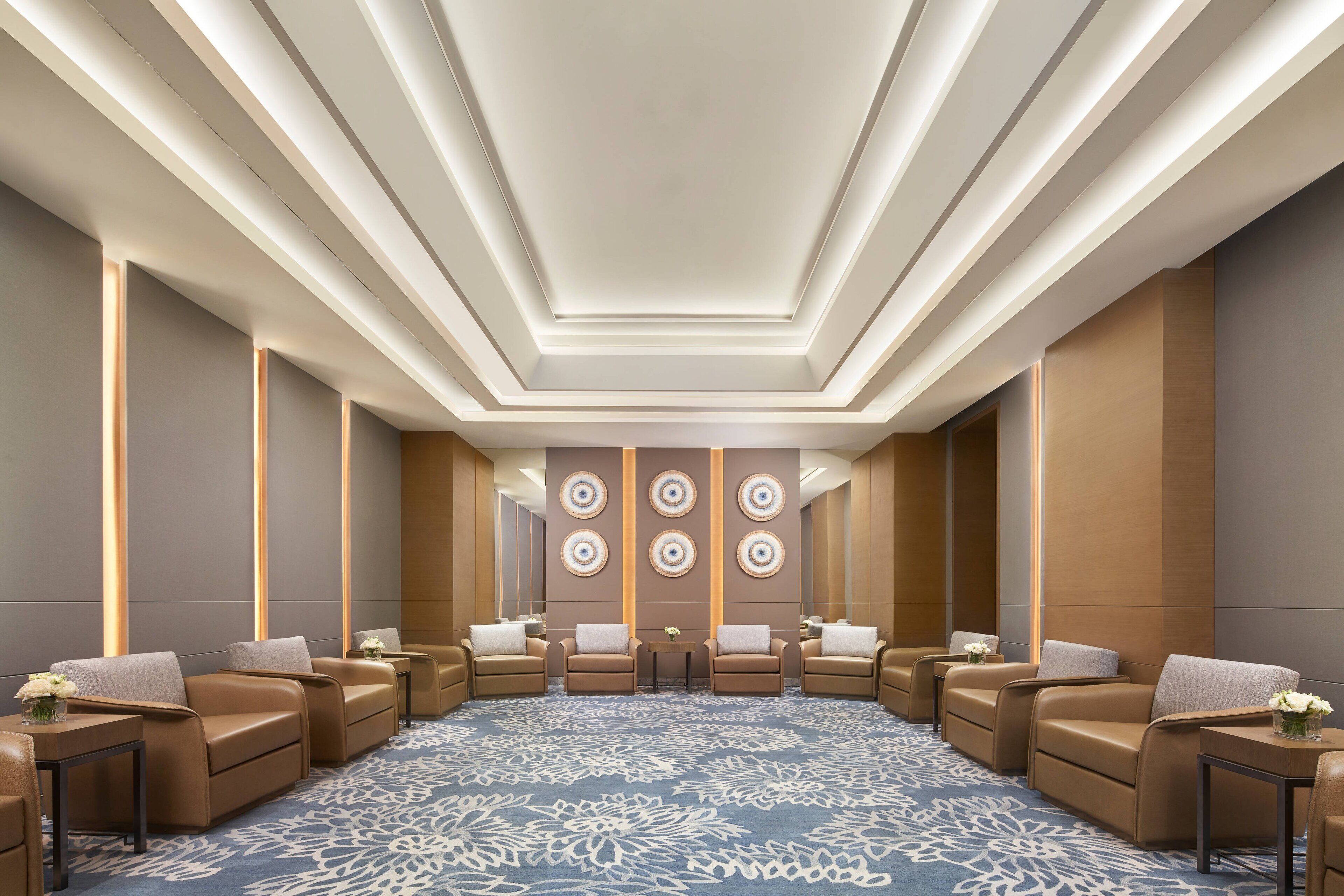 Een hotellobby met een centraal zitgedeelte, een kamerbreed tapijt met dessin en een modern plafondontwerp.