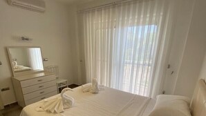 A hotel room with a large bed, a dresser, a mirror, and a window with sheer curtains. - VILLA ZEZE 7 ROOMS 14 SLEEPS PRIVATE WATERSLIDES (Dalyan)