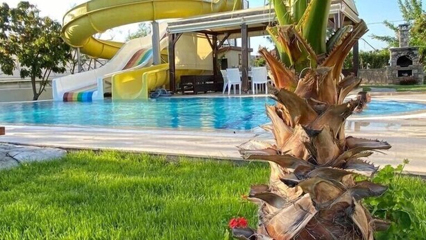 A pool area with a water slide, a covered seating area, and a stone fireplace. - VILLA ZEZE 7 ROOMS 14 SLEEPS PRIVATE WATERSLIDES (Dalyan)