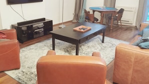 Un salon comprenant un téléviseur, un canapé, une table basse et un coin repas avec une table et des chaises.