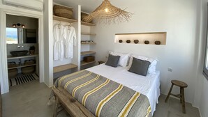 Un dormitorio con cama, mesitas de noche, lámpara colgante y estante empotrado con objetos decorativos.