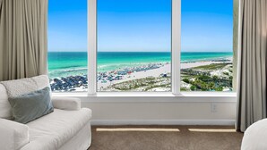 Una habitación con un amplio ventanal que ofrece vistas a una playa y un muelle.