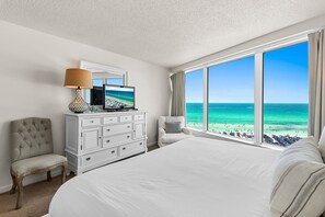 A hotel room with a large bed, a dresser, a chair, a TV, and a view of the beach. - 🌴Sandestin Gulf FRONT~Covered Balcony~Pool-Amazing Views@Beachside Two🌴 (Miramar Beach)