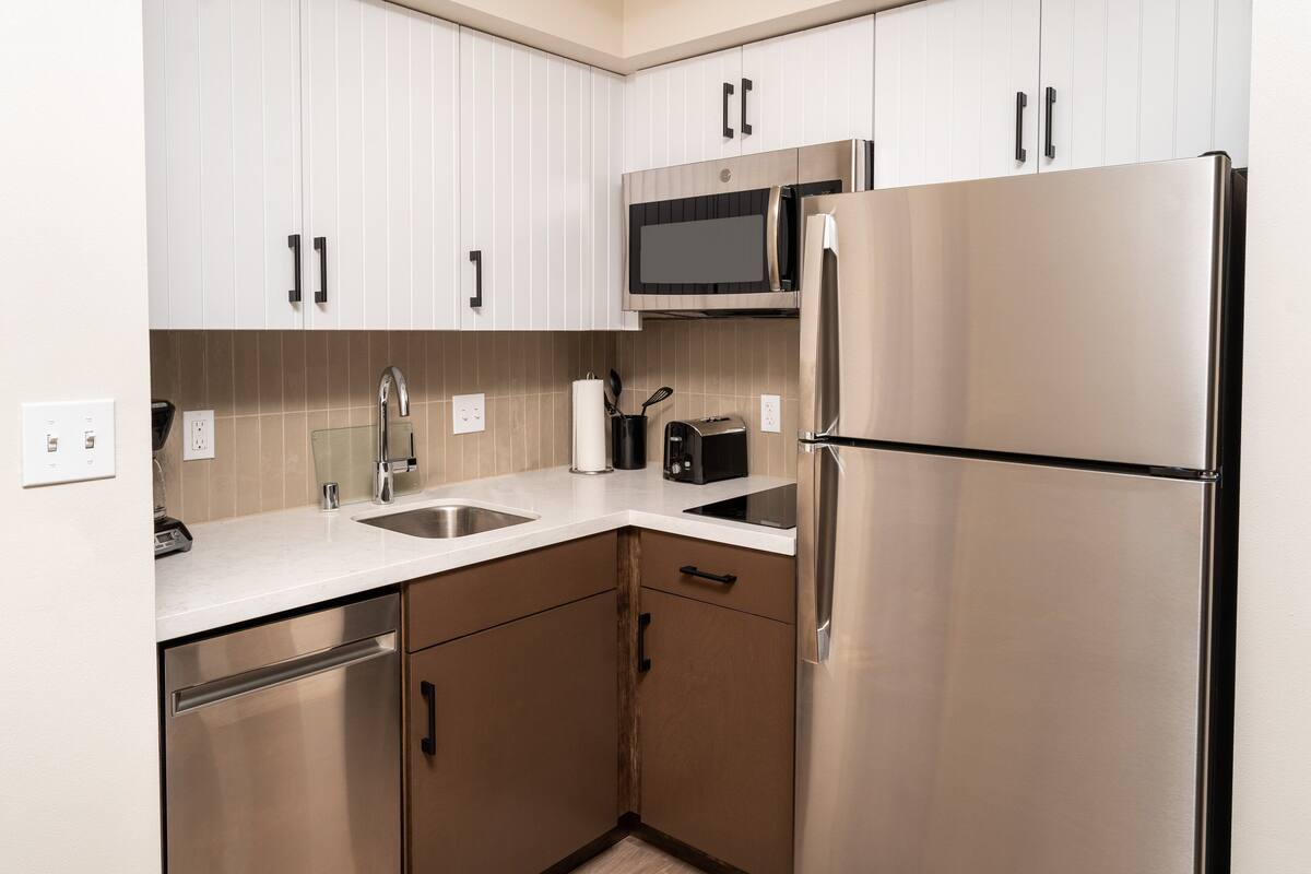 A modern kitchen with stainless steel appliances, white cabinetry, and a built-in microwave.