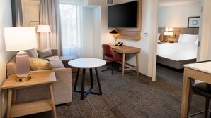 A hotel room with a sofa, a small table, a desk, a bed, a TV, and a bathroom. - Staybridge Suites Temecula Wine Country by IHG (Temecula)