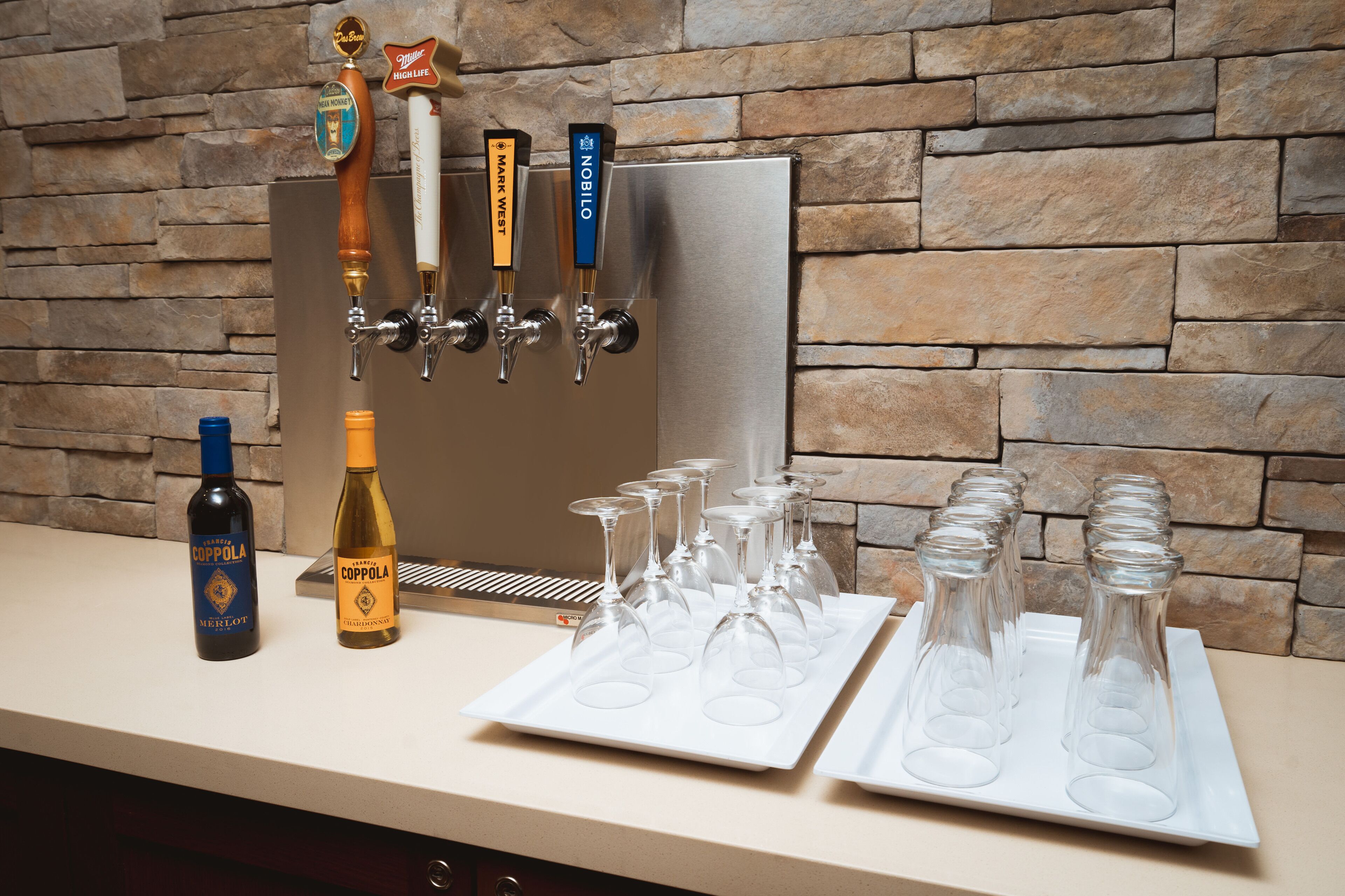 A bar area with multiple taps, glasses, and bottles.
