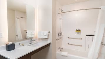 Une salle de bain moderne avec un grand miroir, un lavabo, une baignoire et un espace douche.