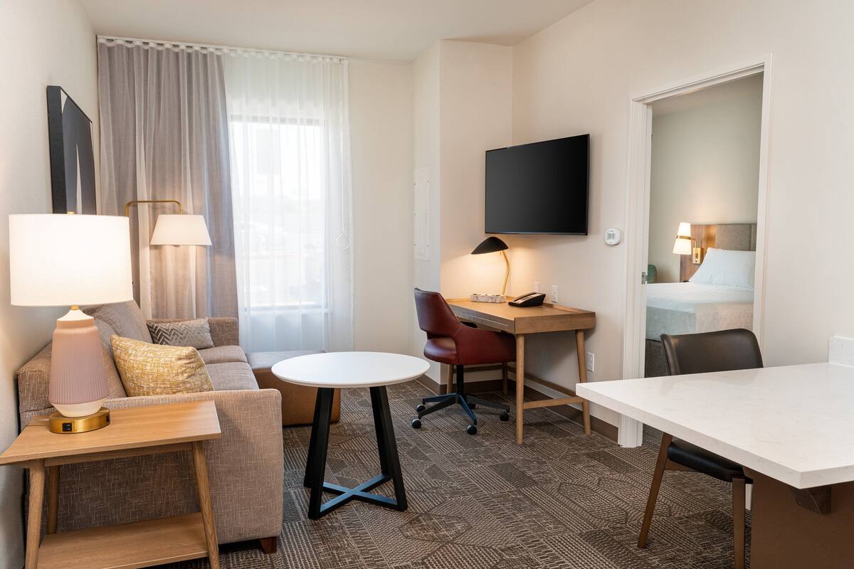 A hotel room with a sofa, a small round table, a desk, and a bed.