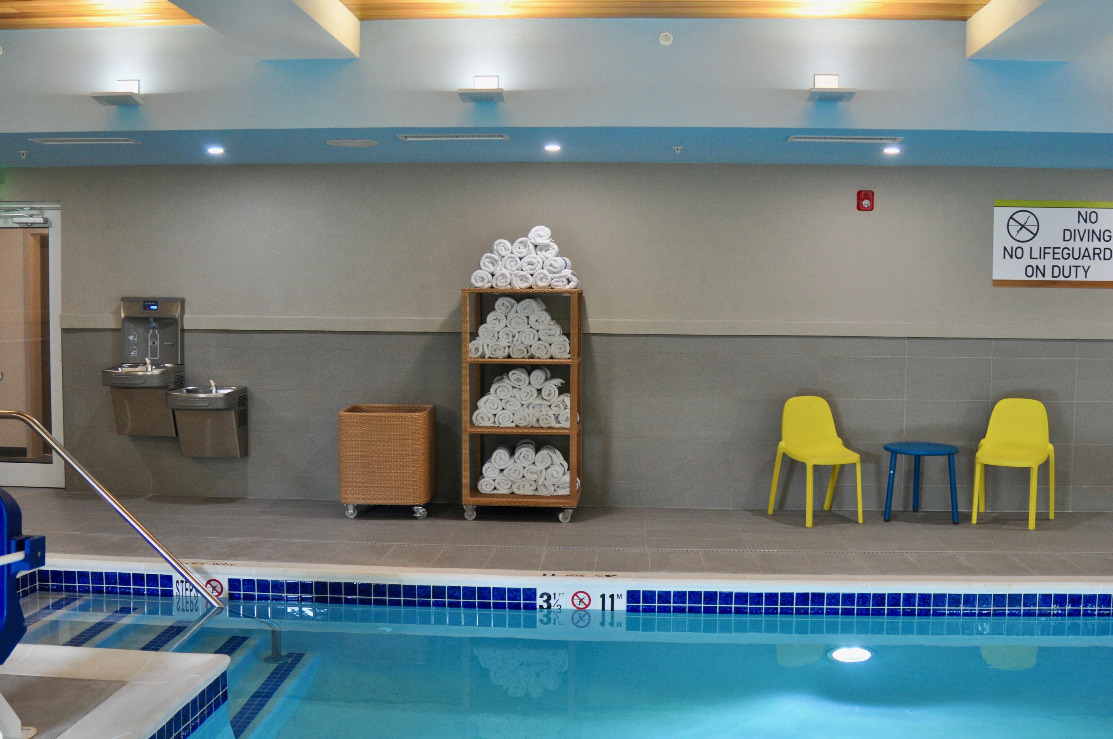A swimming pool area with a sign indicating no diving or lifeguard on duty.