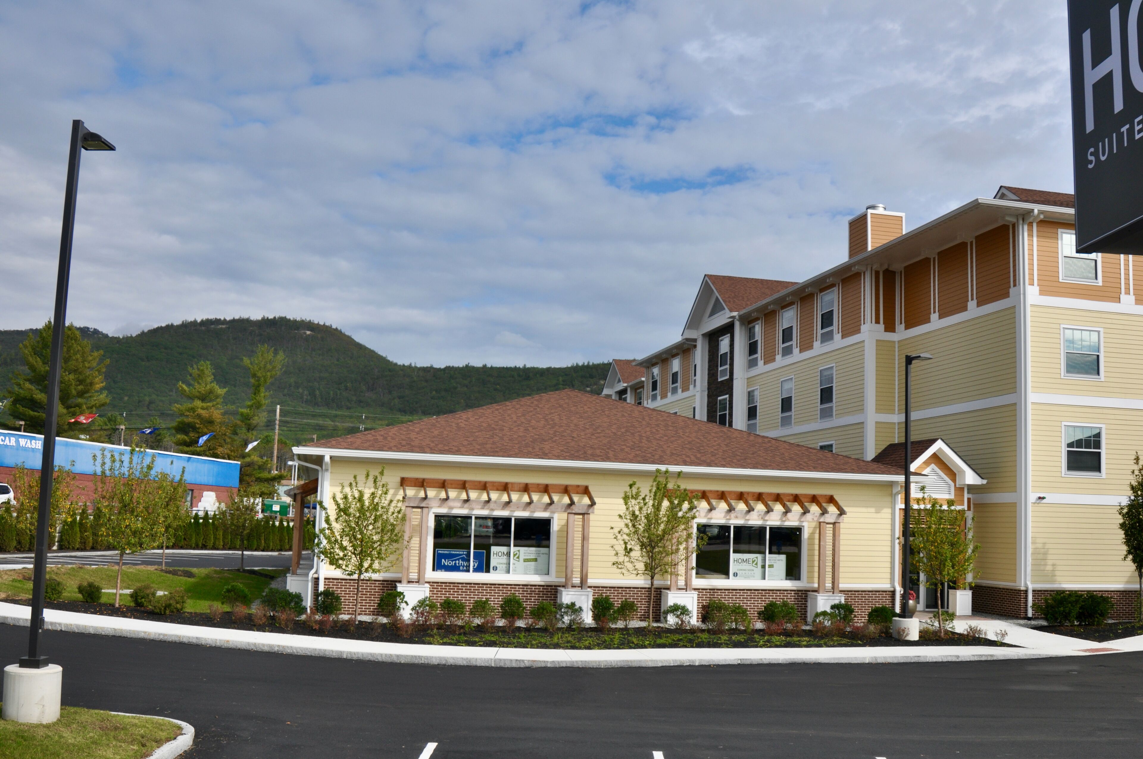 A hotel with a two-story structure, a parking lot, and a mountain in the background.