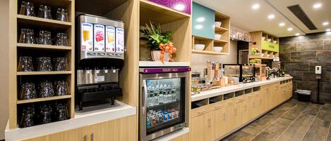 A self-service beverage station with refrigerated drinks and a selection of glassware.