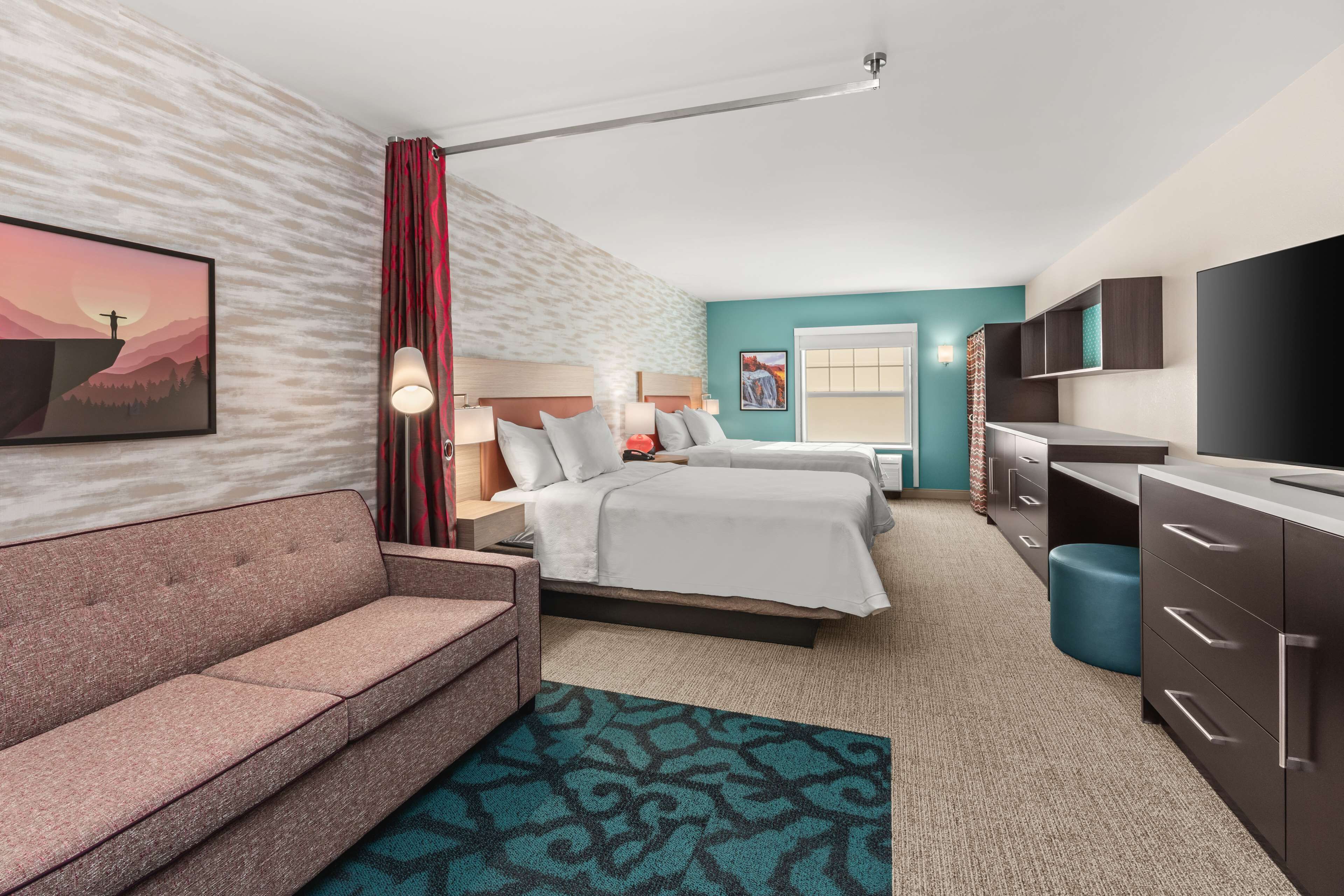 A hotel room with a large bed, a sofa, a desk, and a TV.