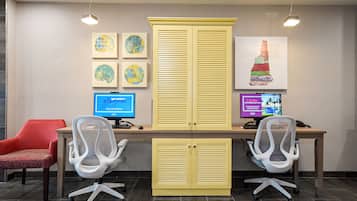 A modern office space with two desks, two office chairs, a red chair, and artwork on the wall.