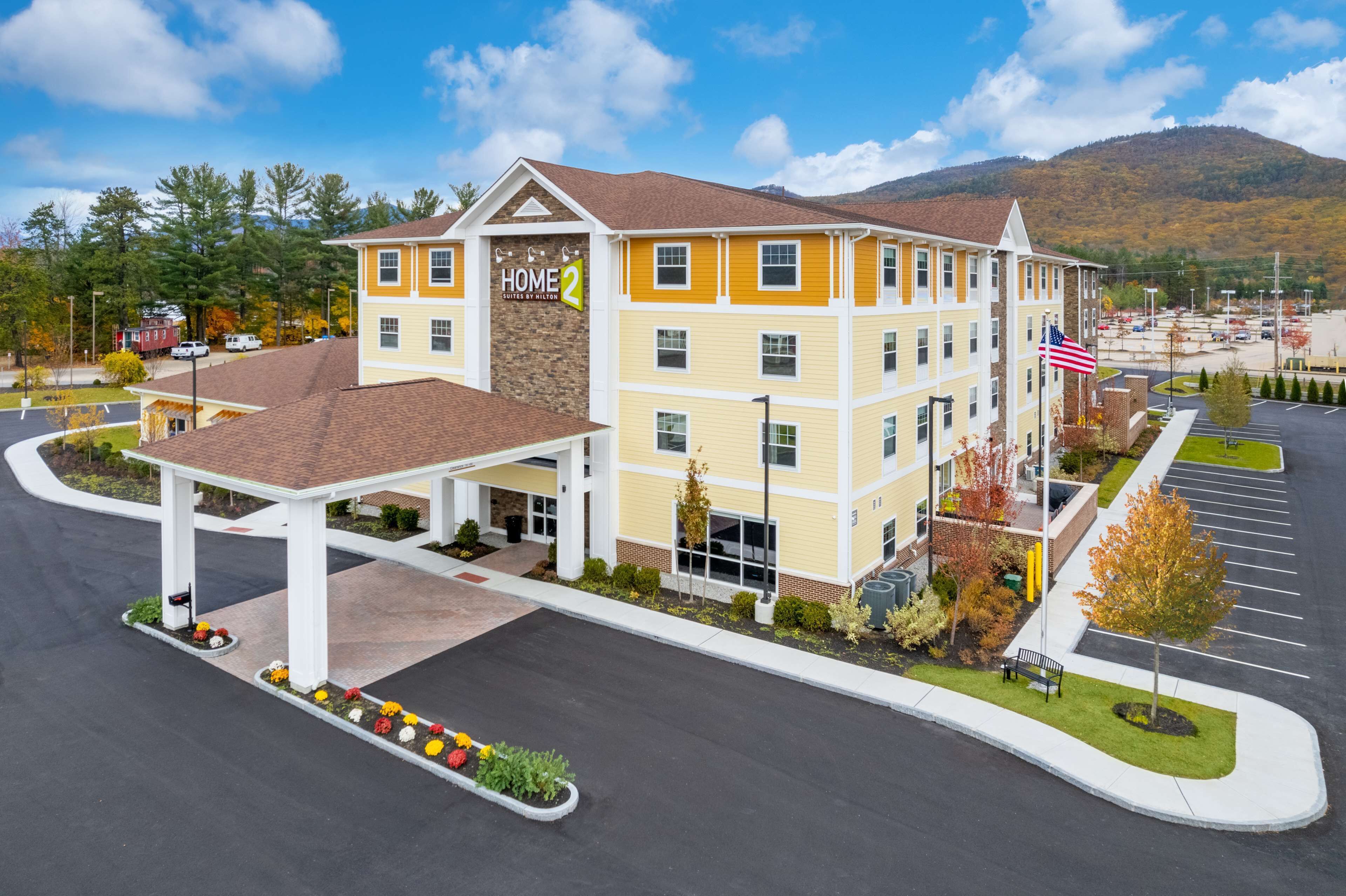 A multi-story hotel with a yellow facade, a covered entrance, and a parking lot.