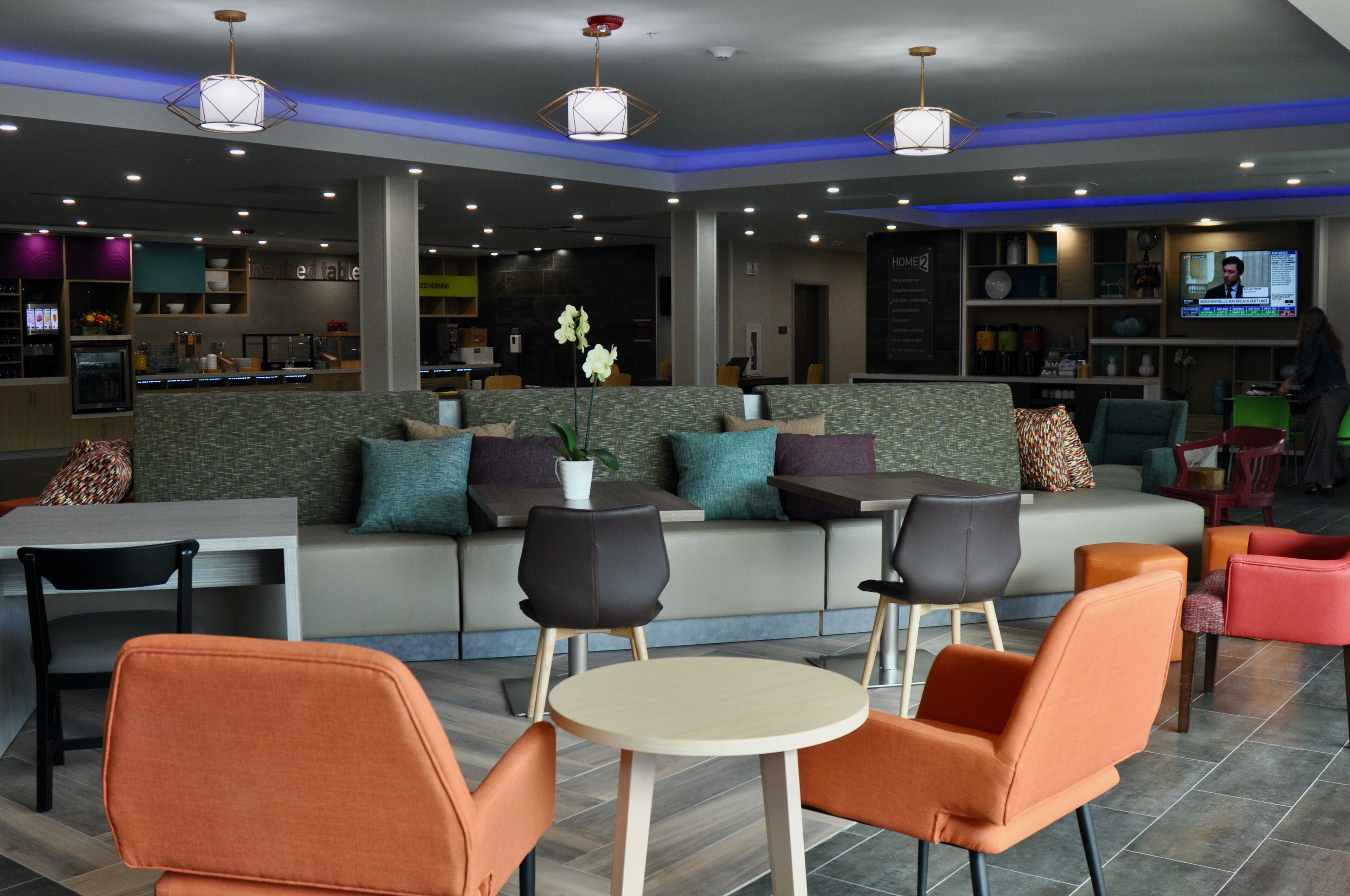 A modern lounge area with seating, a television, and a bar area.