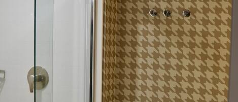 Een badkamer met een douchecabine van glas, een toilet en behang met een patroon.