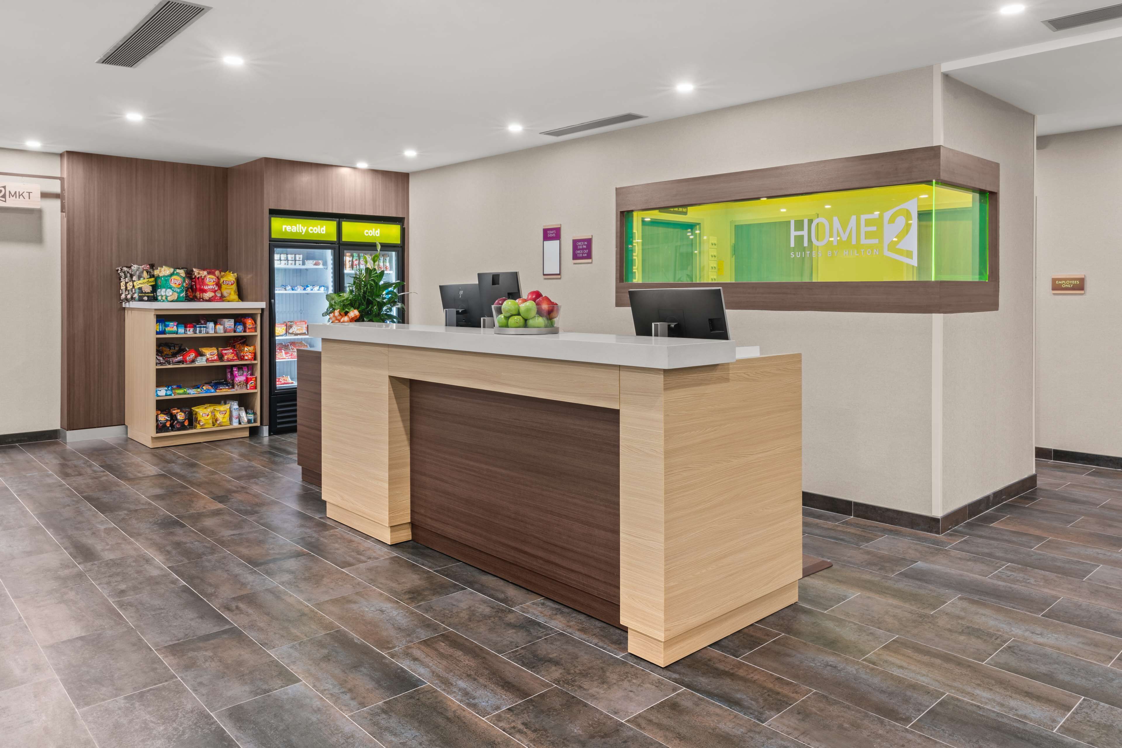 A hotel reception desk with a digital display, a snack bar, and a fruit display.