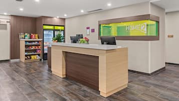 A hotel reception desk with a digital display, a snack bar, and a fruit display.