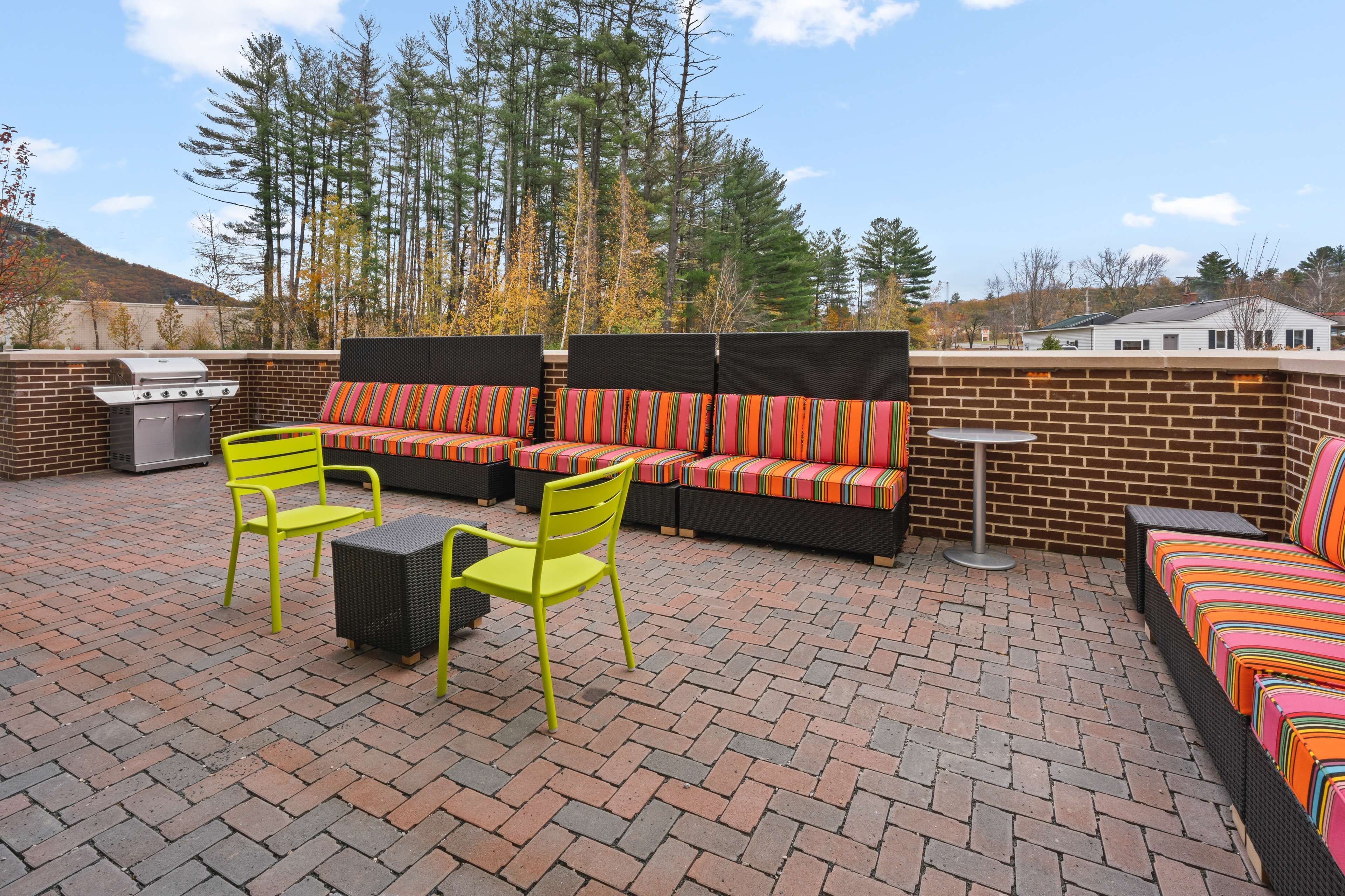An outdoor patio with a brick floor, a grill, a sofa set, and two chairs.
