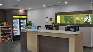 Ein Hotelrezeptionsschalter mit digitalem Bildschirm, einer Minibar und einem Automaten.