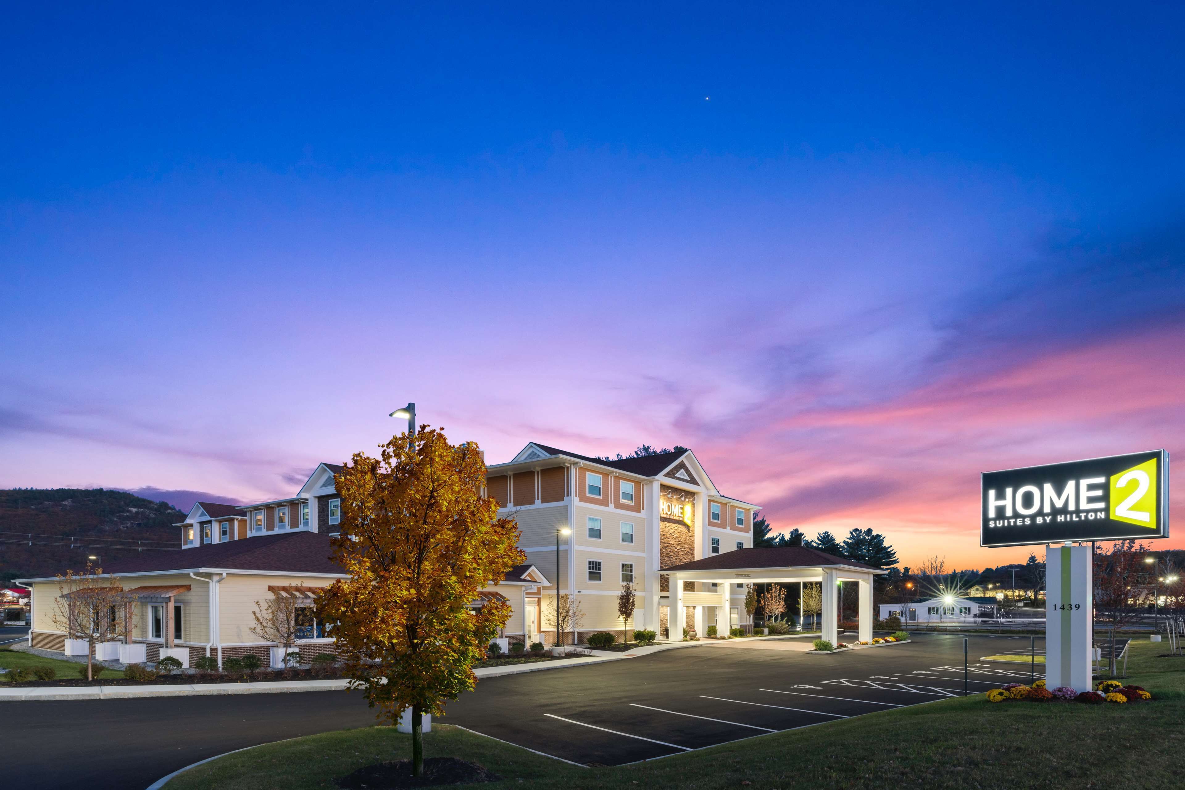 A hotel with a sign reading "HOME 2 Suites by Hilton" and a parking lot.