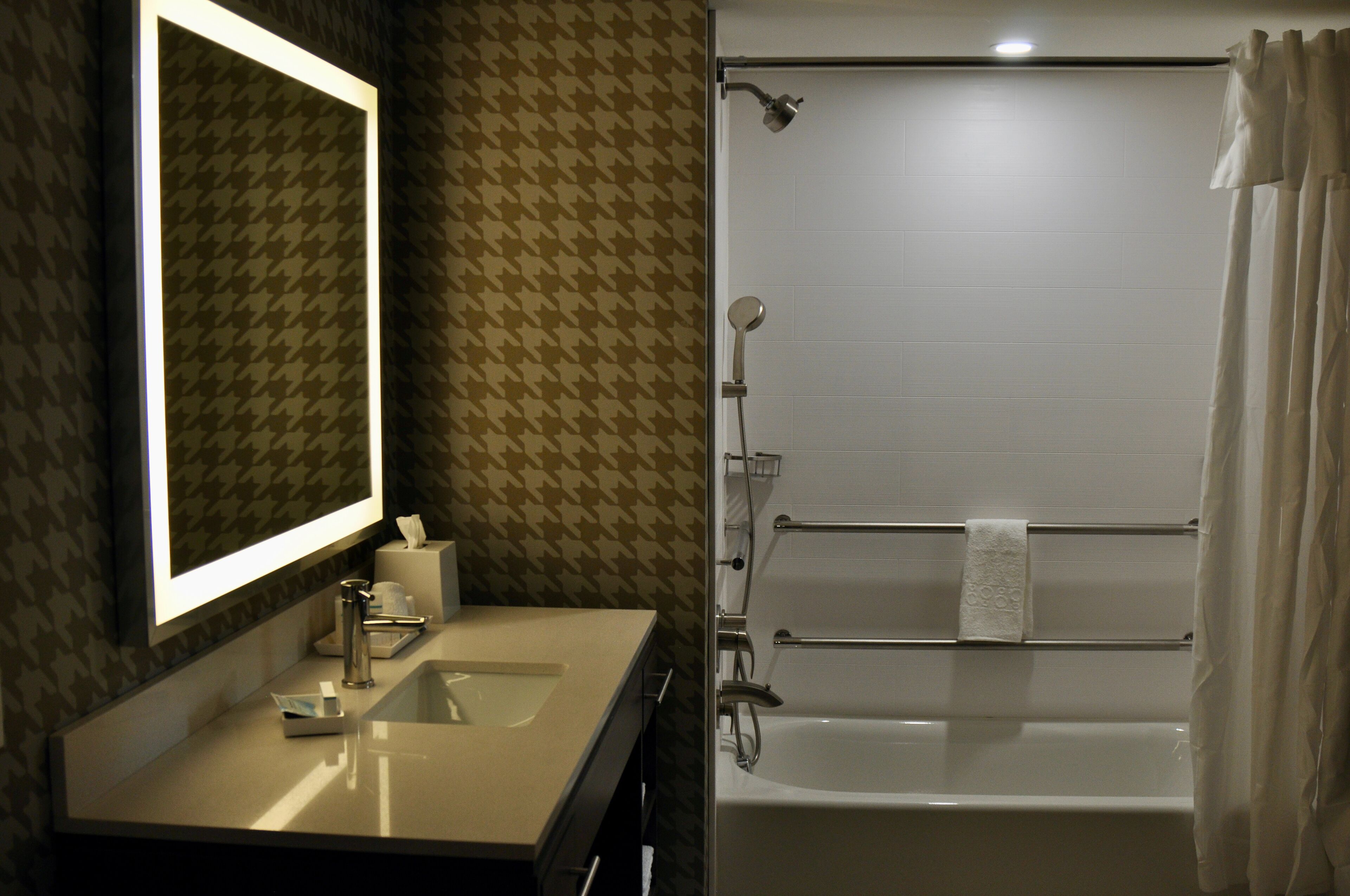 Ein Badezimmer mit Waschbecken, Spiegel, Handtuchhalter und Dusche.