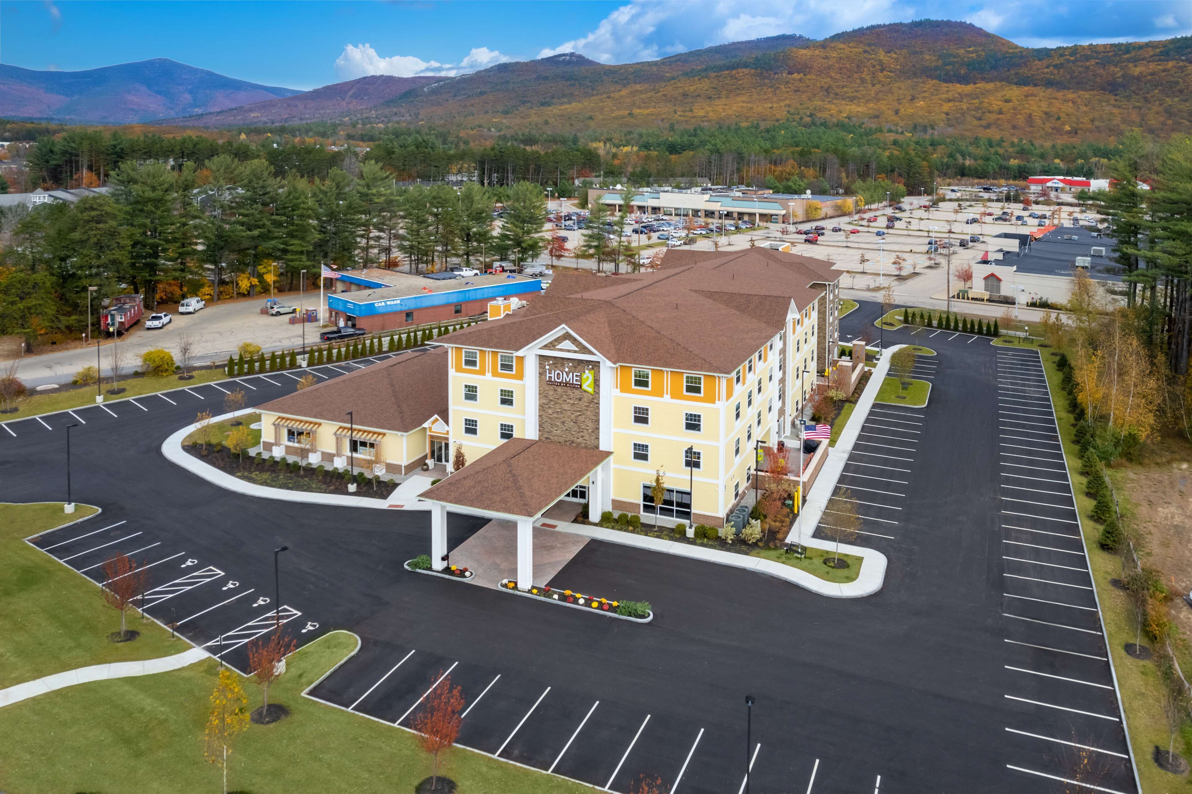 A hotel with a central courtyard, multiple parking lots, and a mountainous backdrop.