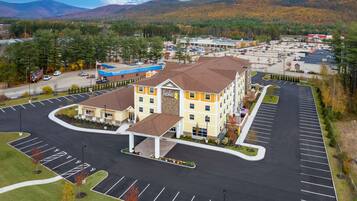 A hotel with a central courtyard, multiple parking lots, and a mountainous backdrop.