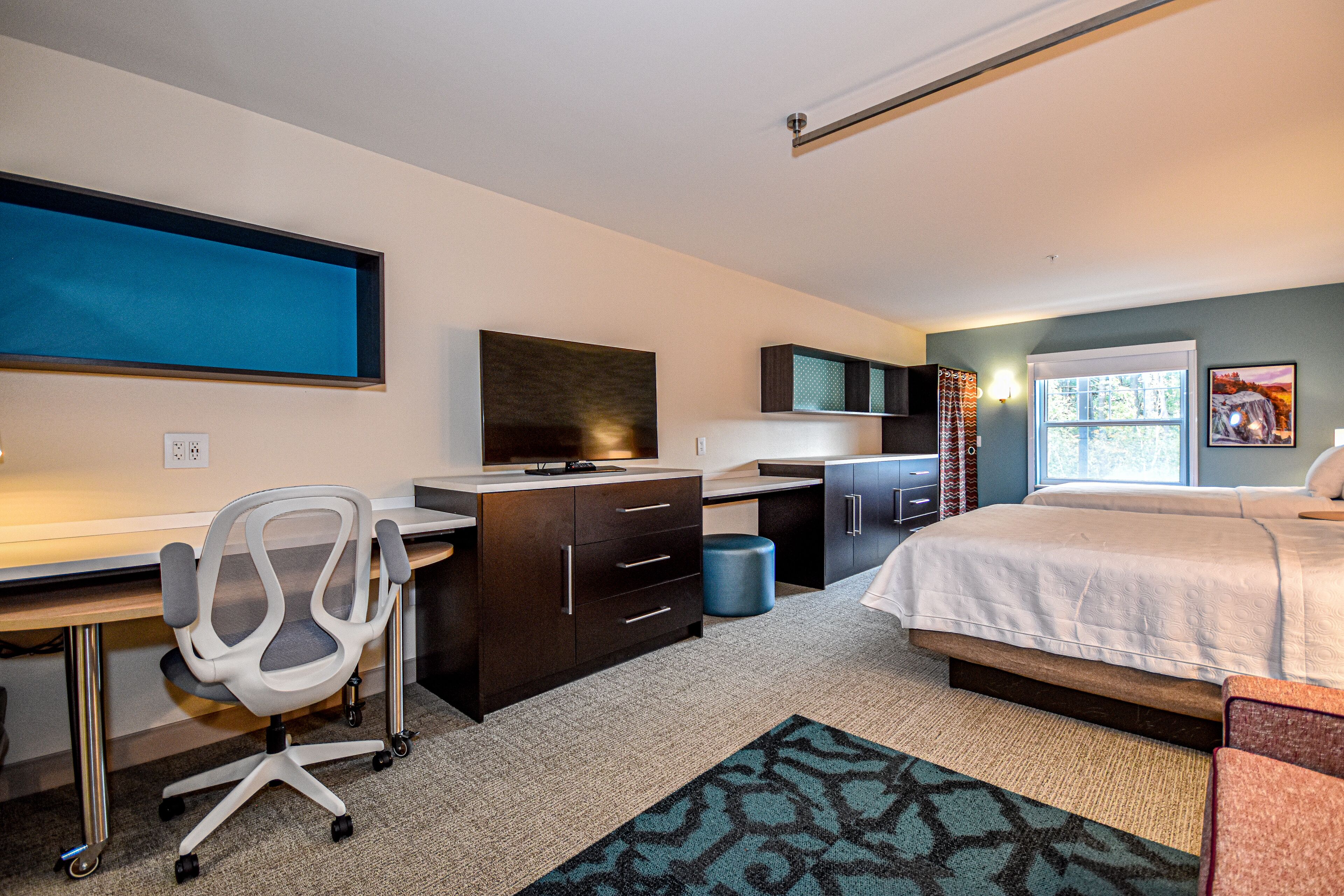 Une chambre à coucher moderne, équipée d’un lit, d’un bureau, d’une chaise et d’un téléviseur.