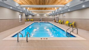 An indoor swimming pool with clear water, wooden ceiling, and yellow chairs around the pool. - Home2 Suites by Hilton North Conway (North Conway)