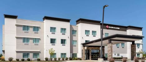 A modern hotel with a flat facade, multiple windows, and a covered entrance area.