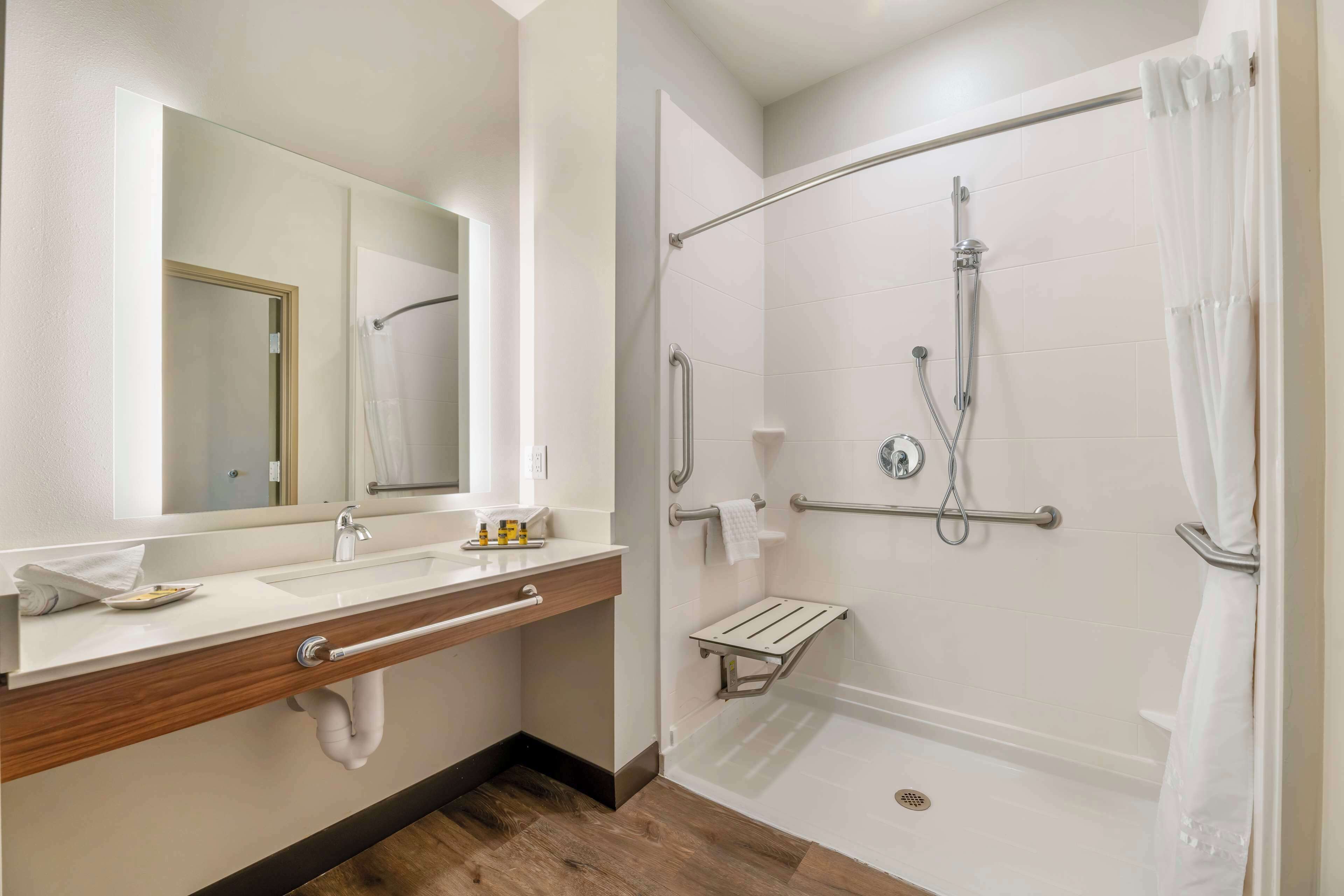 Un baño moderno con lavamanos, espejo y ducha a ras de suelo.