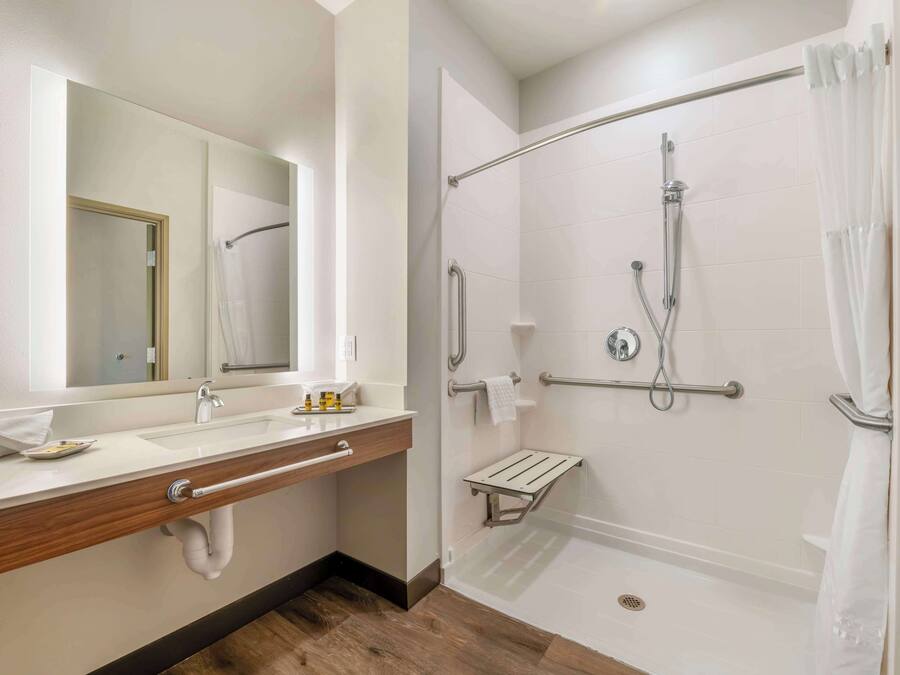 Un baño moderno con lavamanos, espejo y ducha a ras de suelo.