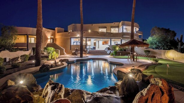 A modern house with a swimming pool, palm trees, and a well-lit patio area. - Happy Valley Hideaway | Resort-like home with amazing views & walking distance to hiking trails! (Phoenix)