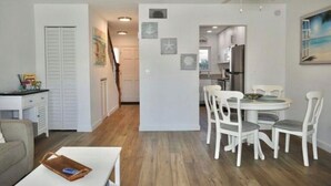 Una sala de estar moderna con un sofá blanco, una mesa de comedor con sillas blancas y un ventilador de techo.