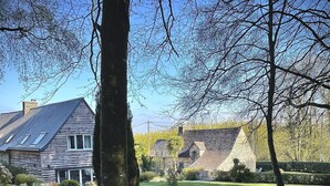 A rustic house with a sloped roof, surrounded by a well-maintained lawn and trees.