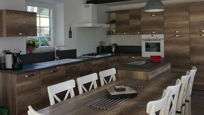 A modern kitchen with a central island, white chairs, and pendant lighting.