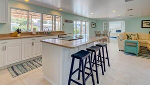 A spacious kitchen with a central island, white cabinets, and a dining area with a sofa and chairs.