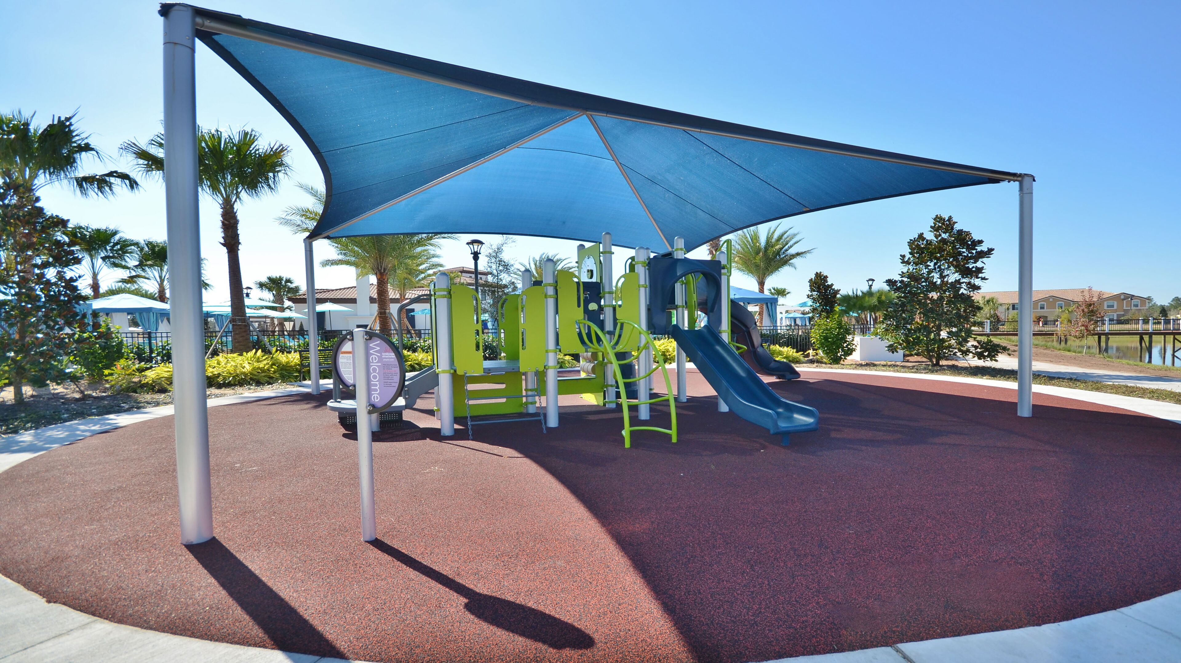 Un parque infantil con tobogán, estructuras para escalar y una zona con sombra.
