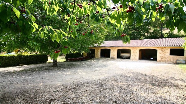 A gravel driveway leading to a building with a tiled roof and three open garage doors.