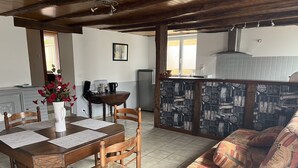 A dining area with a wooden table, chairs, and a vase of flowers. - Rent Sarlat in Perigord  (Sarlat-la-Canéda)